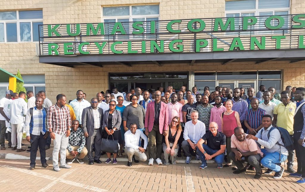 Gruppenfoto vor dem Gebäude der „Kumasi Compost and Recycling Plant“ mit zahlreichen Teilnehmerinnen und Teilnehmern einer Exkursion oder Schulung.