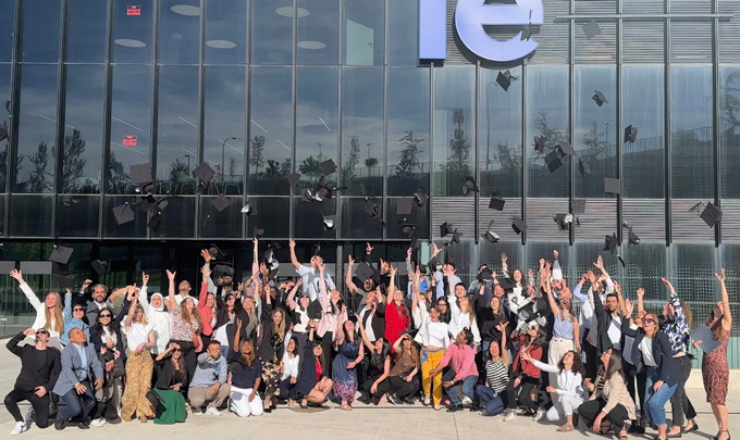 Die gesamte Amex-Belegschaft vor einer Glaswand - sie werfen etwas in die Luft.