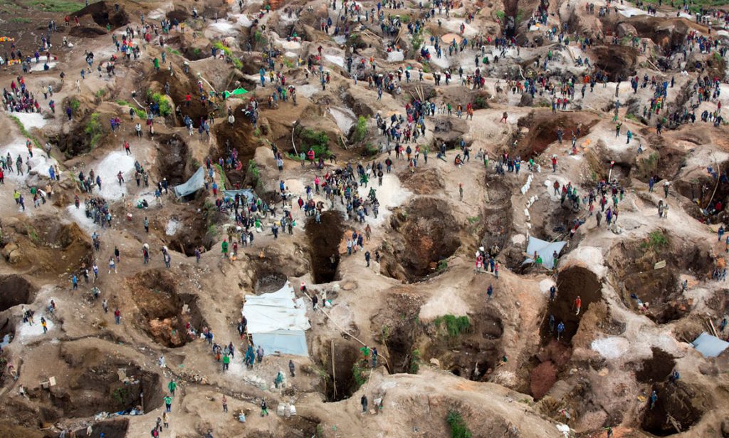 Luftaufnahme eines großflächigen handwerklichen Bergbaugebiets mit vielen Gruben und zahlreichen Menschen, die dort arbeiten.