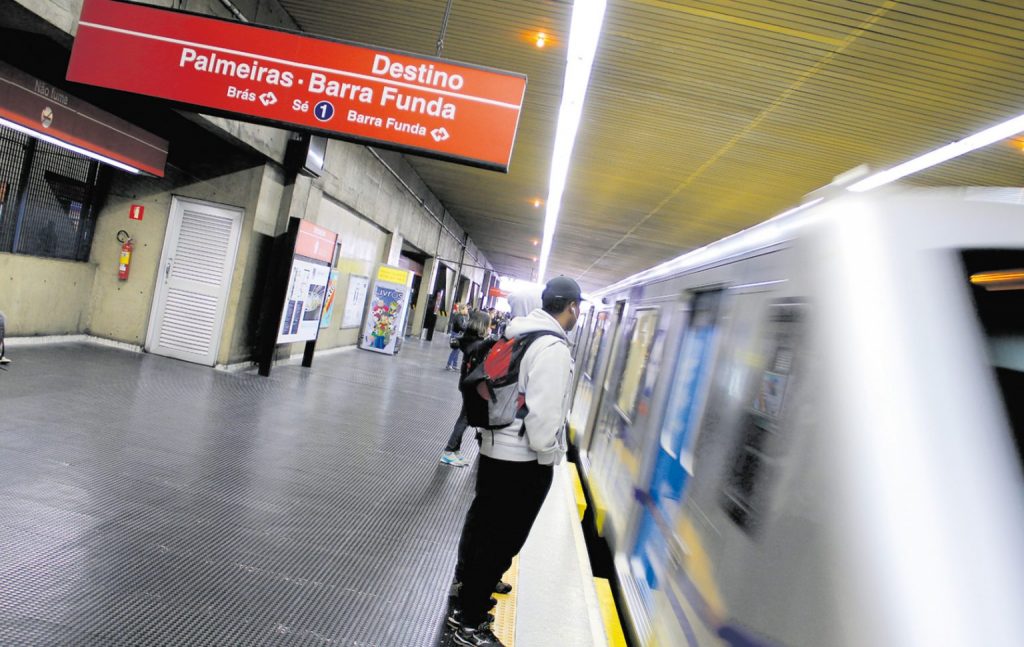 Menschen warten in einer U-Bahn-Station auf einen einfahrenden Zug mit Ziel Palmeiras–Barra Funda.